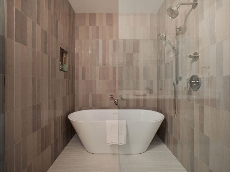 Bathroom featuring tile walls, tile patterned flooring, tiled shower, and a freestanding tub Bathroom featuring tile walls, tile patterned flooring, tiled shower, and a freestanding tub