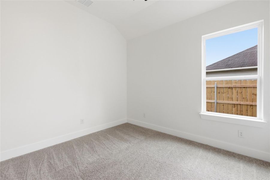 Spare room featuring lofted ceiling and light colored carpet