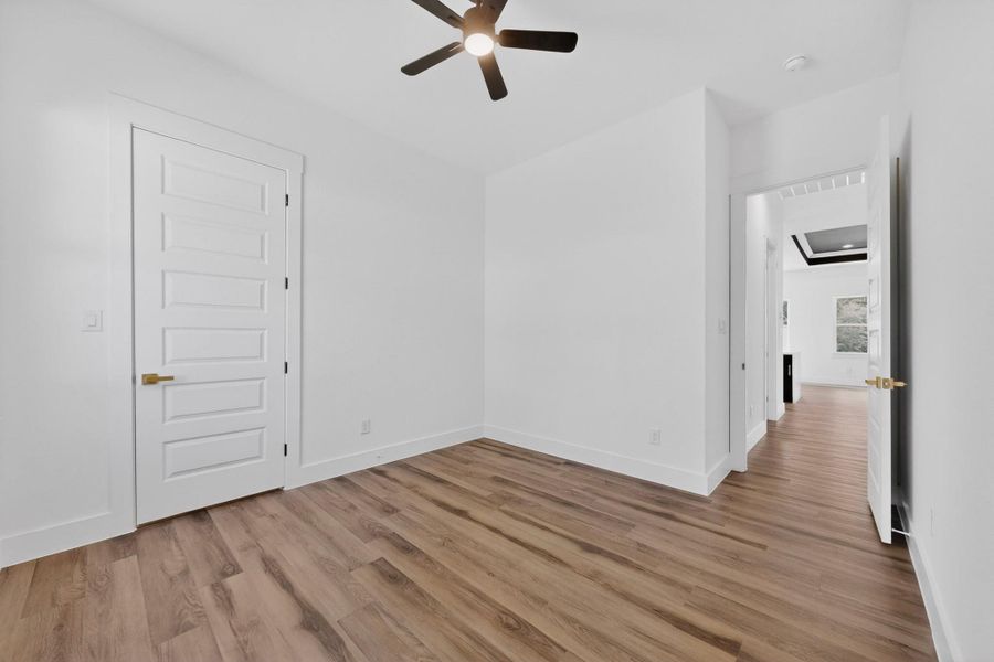 A well-lit room showcasing a contemporary ceiling fan and durable hardwood flooring.