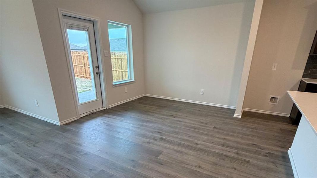 Unfurnished dining area with lofted ceiling and dark wood-style flooring