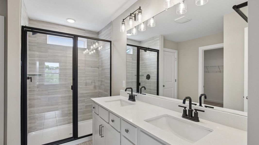 Bathroom with tile shower and glass enclosure, along with dual vanity