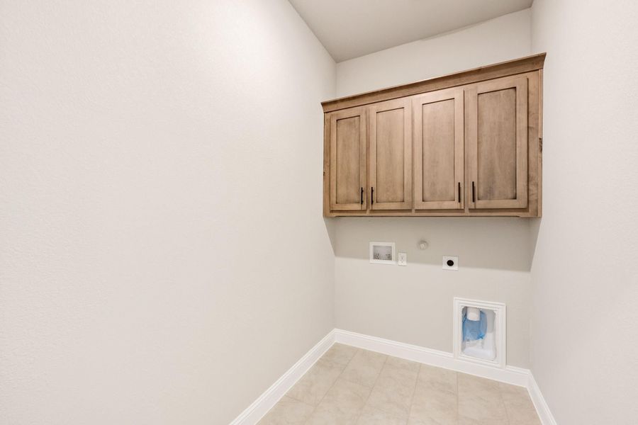 Laundry room with upper wood cabinets, washer and dryer hookups, and tile flooring Laundry room with upper wood cabinets, washer and dryer hookups, and tile flooring