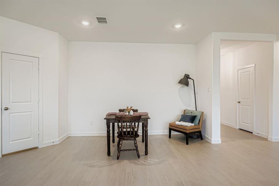 Sitting room with light wood finished floors and recessed lighting