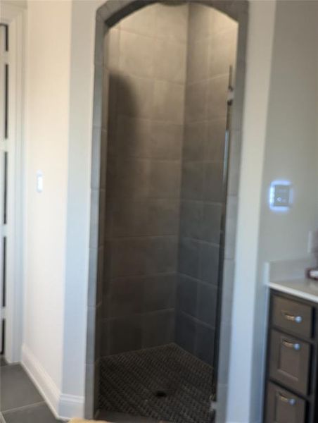 Bathroom featuring a tile shower, tile patterned floors, and vanity