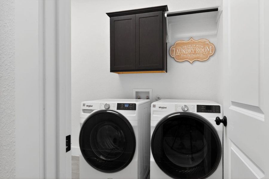 Dedicated laundry space featuring a dark wood-finish wall cabinet, a built-in folding rack, and light-toned wall paint Dedicated laundry space featuring a dark wood-finish wall cabinet, a built-in folding rack, and light-toned wall paint