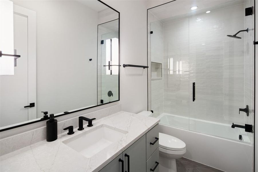 Stylish ensuite bathroom featuring a glass-enclosed shower and tub combination with upgraded tile surround, a spacious vanity with modern finishes, and designer lighting that adds a polished, contemporary touch.