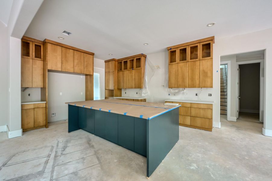 A spacious kitchen with light wood cabinets, a large central island, and ample storage space and a walk-in pantry.
