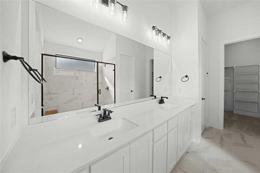 Full bath featuring a marble finish shower, double vanity, light marble finish floors, and a spacious closet Full bath featuring a marble finish shower, double vanity, light marble finish floors, and a spacious closet