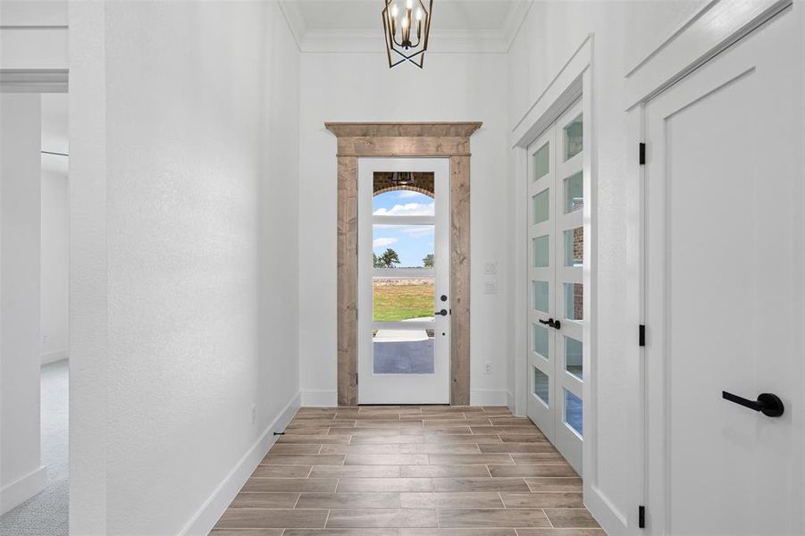 Doorway featuring wood tiled floors, a chandelier, and crown molding Doorway featuring wood tiled floors, a chandelier, and crown molding