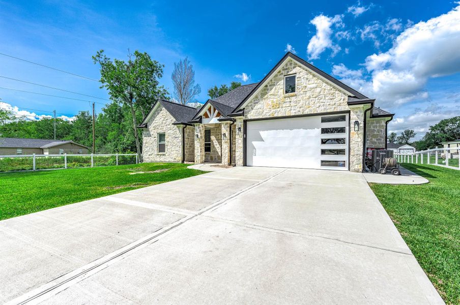 This view highlights the home’s attractive stone exterior, spacious driveway, and attached two-car garage. The well-maintained landscaping and peaceful surroundings add to the property’s overall curb appeal and welcoming atmosphere.
