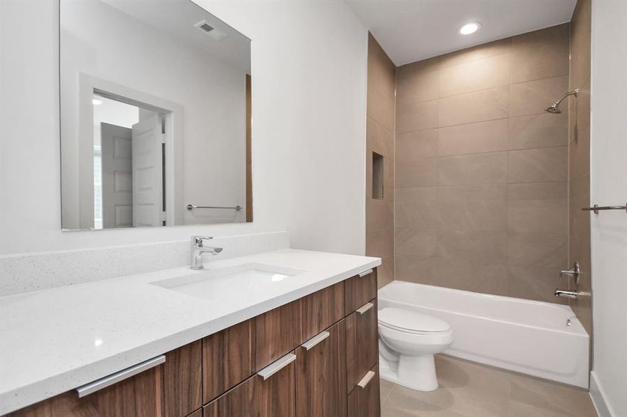 Full Bathroom with Quartz Countertops and Tiled to Ceiling Walls