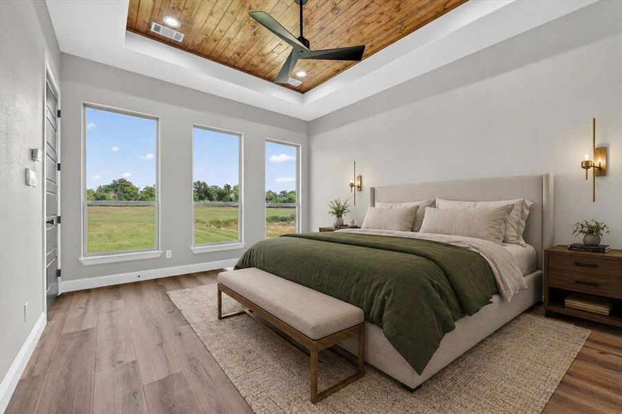 Spacious room featuring a wood-finish tray ceiling with a black ceiling fan, three vertical windows, wood-finish flooring, and two wall-mounted sconces