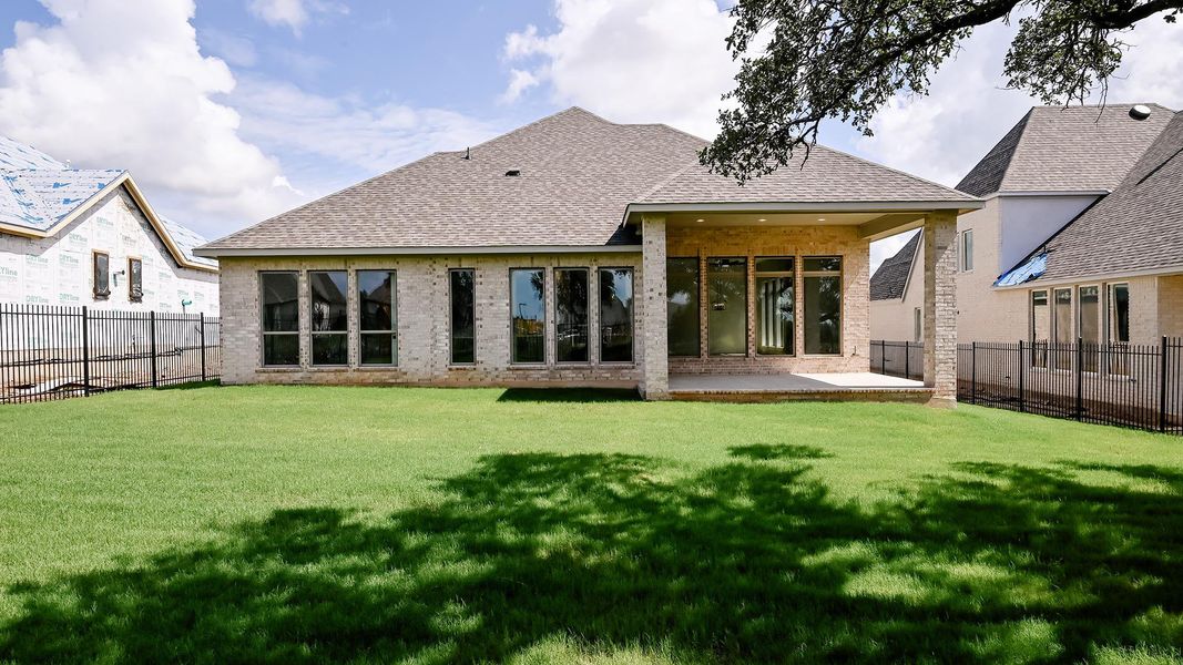 Back of property with a shingled roof, a patio area, brick siding, and a fenced backyard Back of property with a shingled roof, a patio area, brick siding, and a fenced backyard