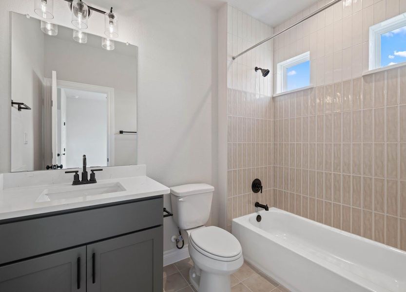 Bathroom featuring tile patterned floors, a healthy amount of sunlight, toilet, and shower / bathing tub combination Bathroom featuring tile patterned floors, a healthy amount of sunlight, toilet, and shower / bathing tub combination