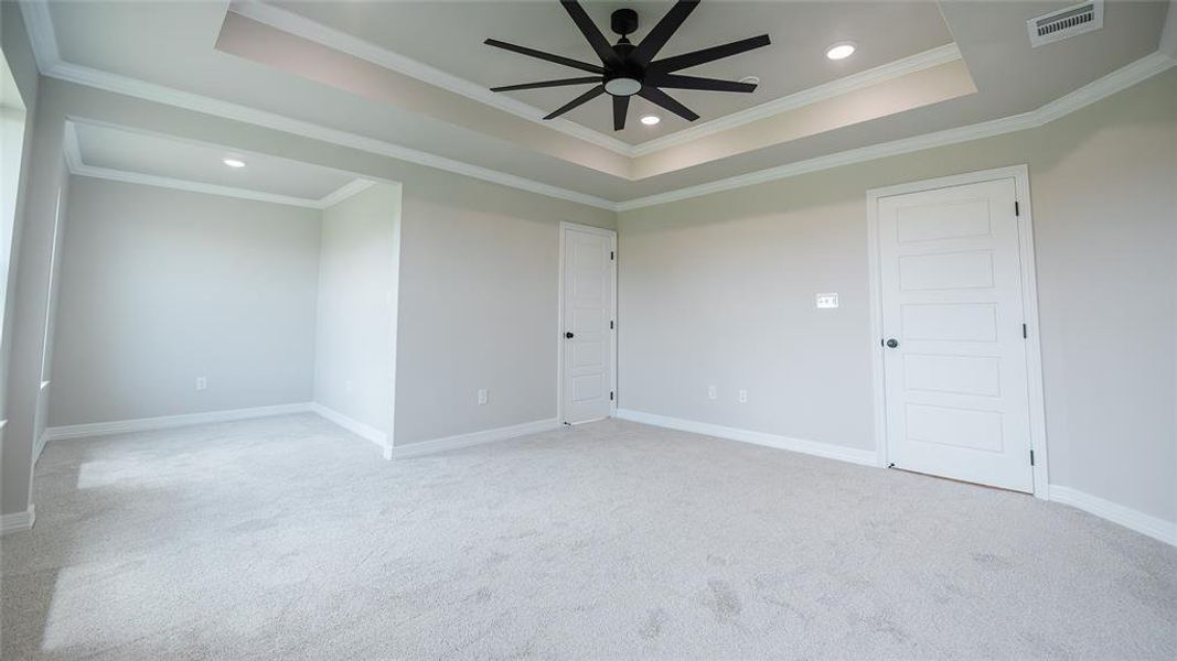 Carpeted empty room with recessed lighting, a ceiling fan, ornamental molding, and a raised ceiling Carpeted empty room with recessed lighting, a ceiling fan, ornamental molding, and a raised ceiling