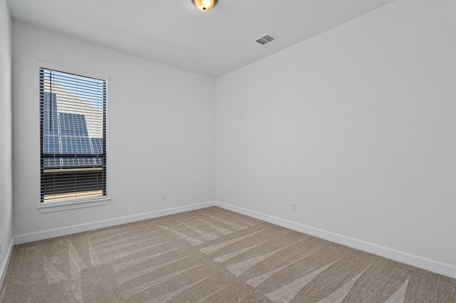 Bright room featuring a window with integrated blinds, neutral-toned carpet, white baseboards, and a ceiling-mounted light fixture