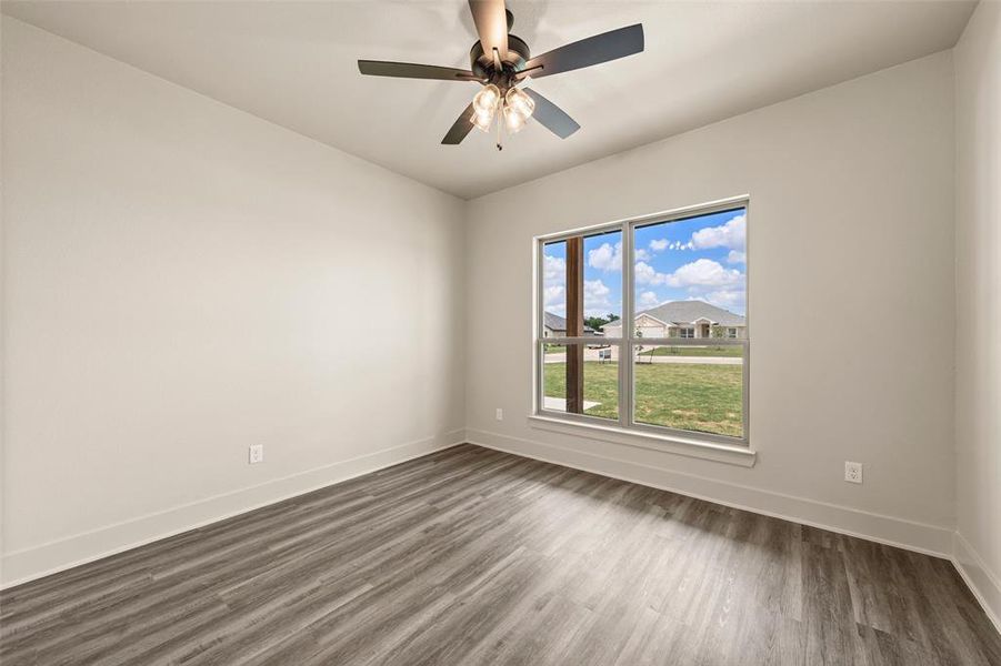 Room featuring wood-finish flooring, a contemporary ceiling fan with integrated lighting, and a large window providing ample natural light Room featuring wood-finish flooring, a contemporary ceiling fan with integrated lighting, and a large window providing ample natural light