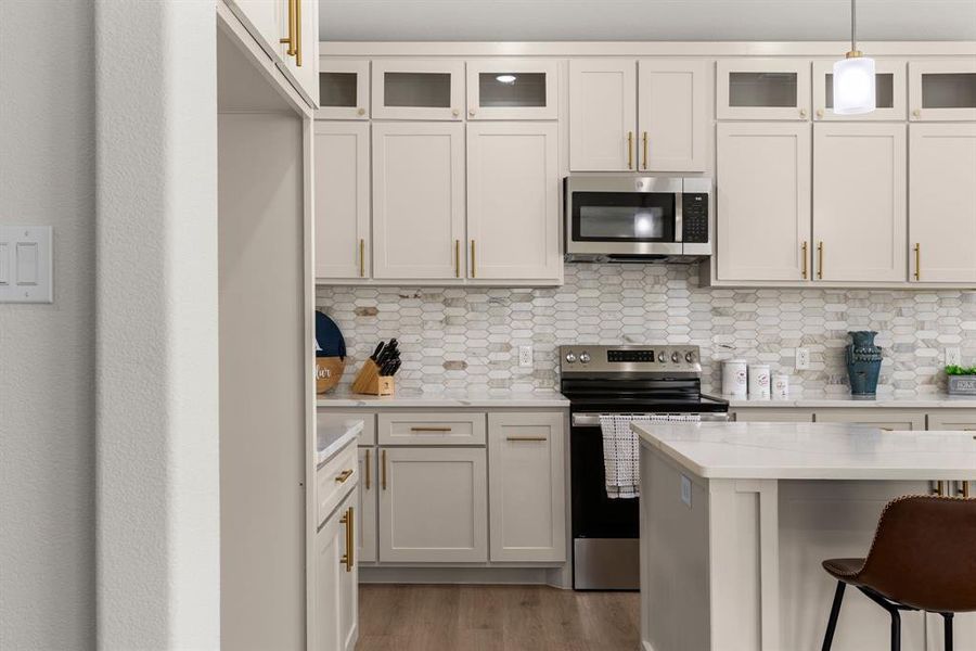 Kitchen with white cabinetry, appliances with stainless steel finishes, a breakfast bar, and decorative light fixtures