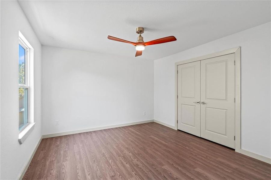 Unfurnished bedroom with dark wood-style floors, ceiling fan, and a closet