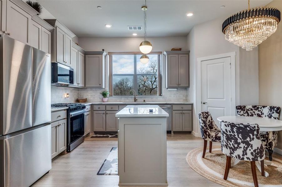View of Kitchen and Eat-In Area with Decorative Lighting
