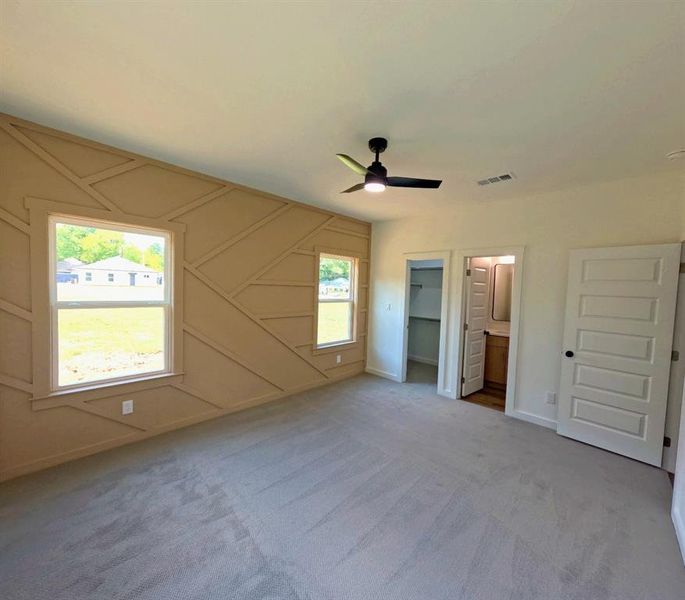 Unfurnished bedroom with a decorative wall, a spacious closet, carpet flooring, a ceiling fan, and connected bathroom Unfurnished bedroom with a decorative wall, a spacious closet, carpet flooring, a ceiling fan, and connected bathroom