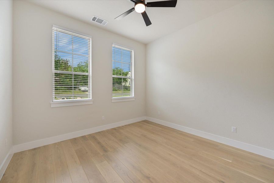 Well-lit interior space with sleek hardwood floors and a modern ceiling fan for comfort.