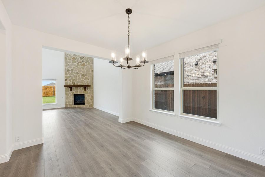 Open dining area with chandelier and hardwood floors, adjacent to living room with stone fireplace Open dining area with chandelier and hardwood floors, adjacent to living room with stone fireplace