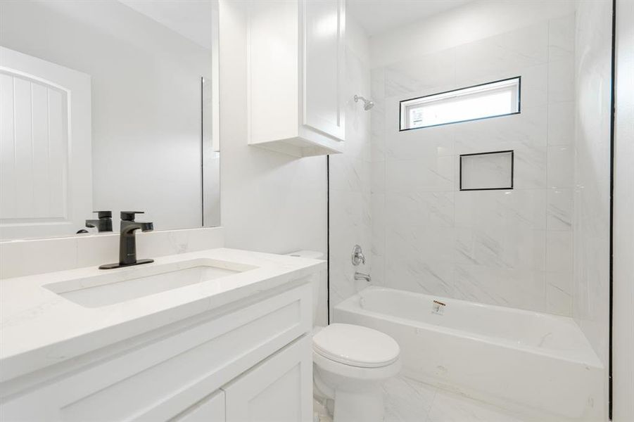 Full bathroom featuring tiled shower / bath, toilet, and vanity