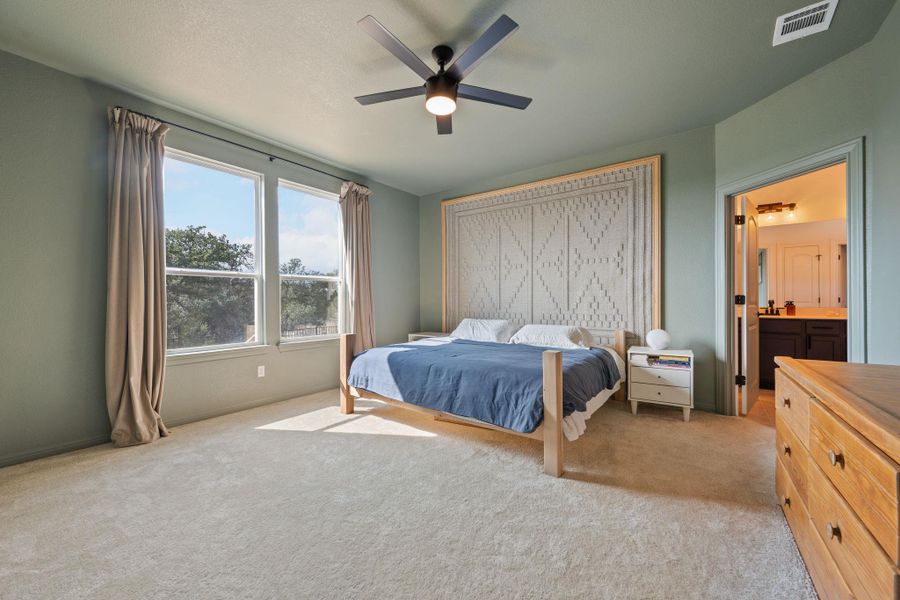 Bedroom featuring light carpet, ceiling fan, and ensuite bathroom Bedroom featuring light carpet, ceiling fan, and ensuite bathroom