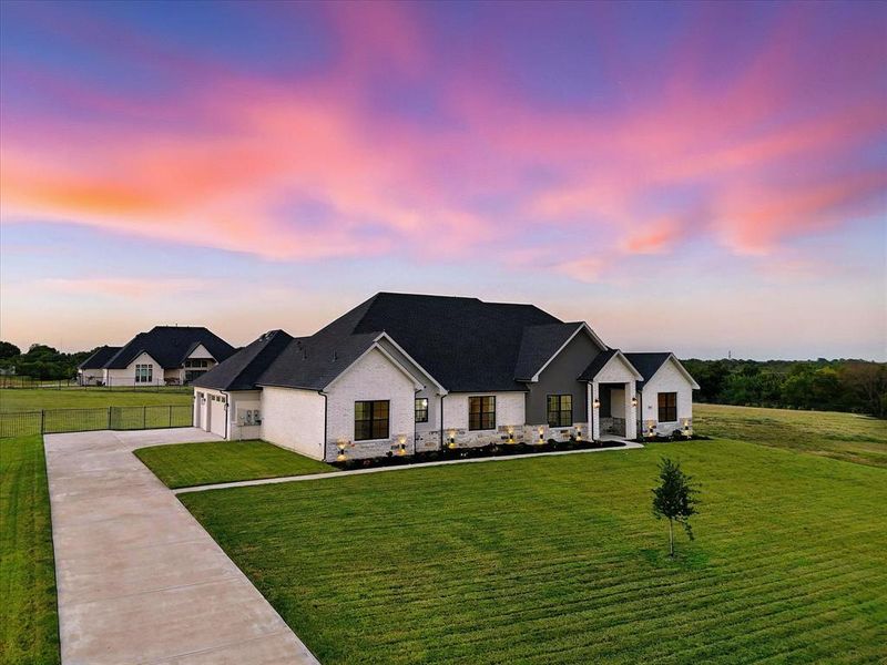 View of front facade featuring stone siding, driveway, and an attached garage View of front facade featuring stone siding, driveway, and an attached garage
