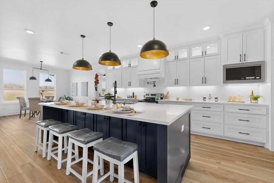 Kitchen with pendant lighting, a kitchen bar, light wood-type flooring, glass insert cabinets, and dual tone cabinetry Kitchen with pendant lighting, a kitchen bar, light wood-type flooring, glass insert cabinets, and dual tone cabinetry