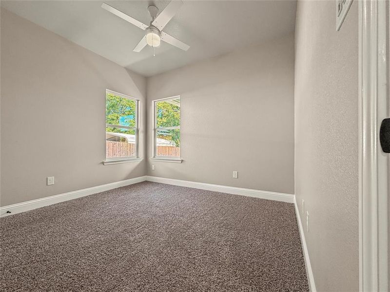 Room featuring vaulted ceilings, two windows, wall-to-wall carpeting, white trim, and a ceiling fan with integrated lighting Room featuring vaulted ceilings, two windows, wall-to-wall carpeting, white trim, and a ceiling fan with integrated lighting