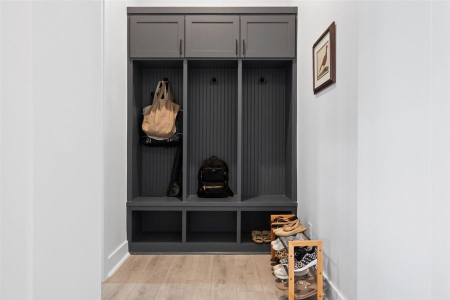 Built-in mudroom storage featuring three individual compartments with upper cabinetry, beadboard backing, and lower cubbies
