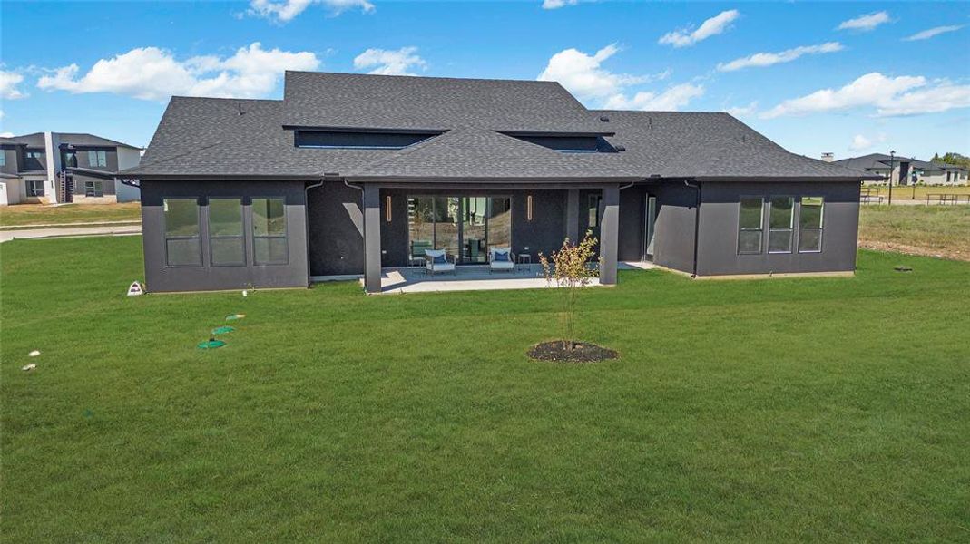 Contemporary rear exterior featuring dark stucco siding, a covered patio, and large sliding glass doors Contemporary rear exterior featuring dark stucco siding, a covered patio, and large sliding glass doors