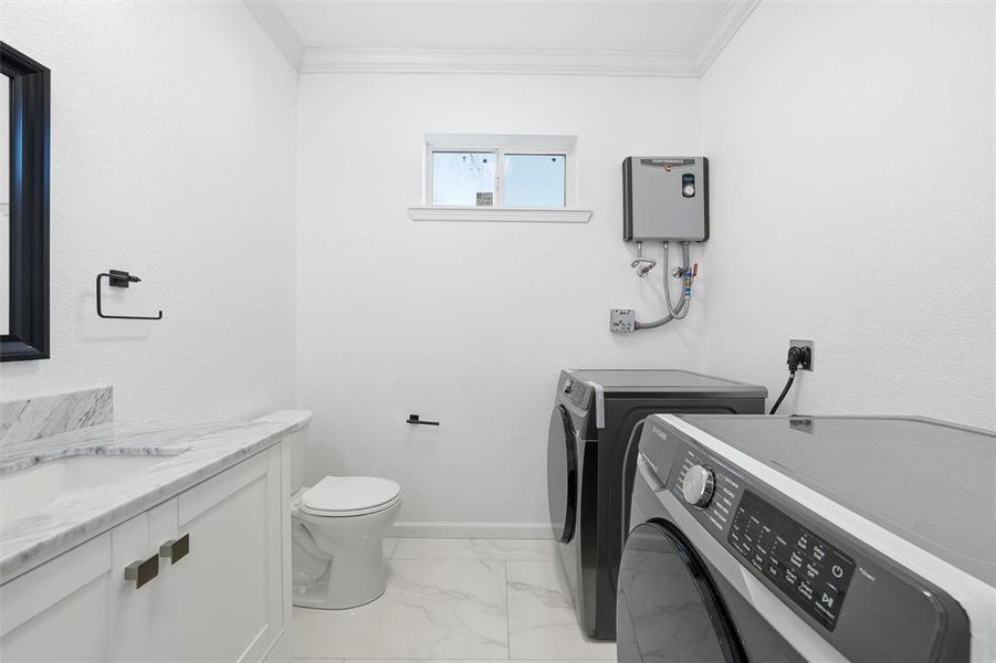 Laundry area featuring light marble finish floors, ornamental molding, separate washer and dryer, and water heater Laundry area featuring light marble finish floors, ornamental molding, separate washer and dryer, and water heater