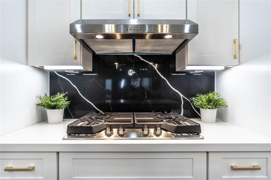 Gas stove and under-cabinet range hood with counter space on both sides for utensils and cooking equipment.