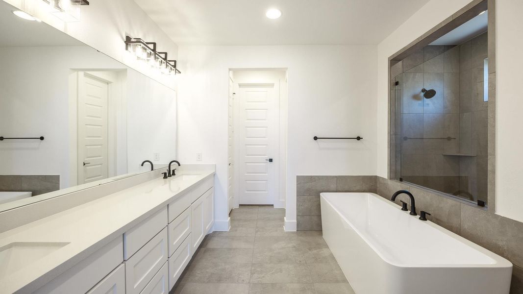 Full bath featuring a freestanding tub, double vanity, recessed lighting, light tile patterned floors, and a tile shower Full bath featuring a freestanding tub, double vanity, recessed lighting, light tile patterned floors, and a tile shower