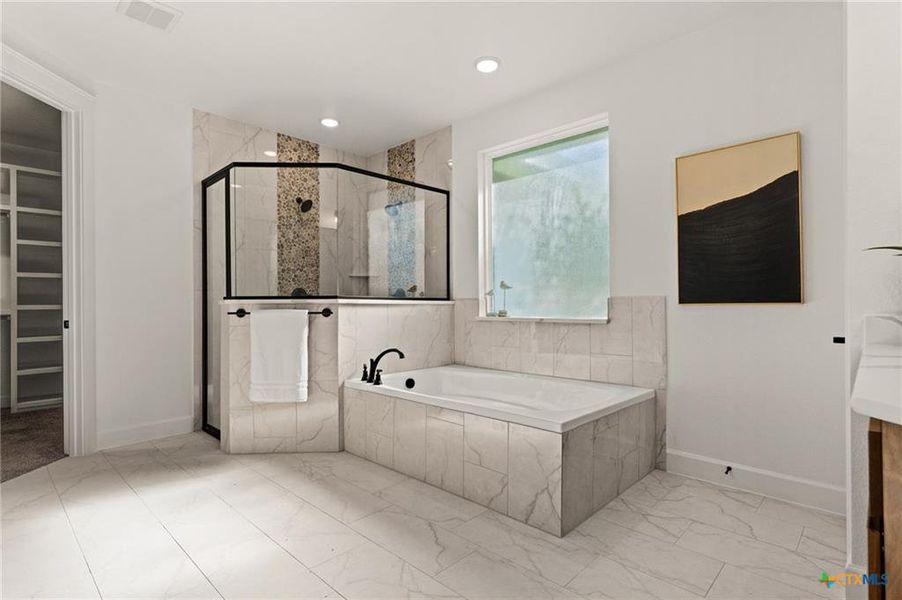 Bathroom with a spacious closet, a shower stall, a bath, and light marble finish floors