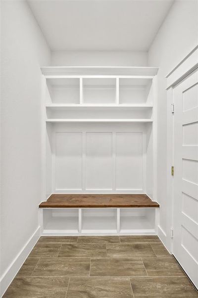 Built-in storage bench featuring a wood-finish seat, white cabinetry, and upper shelving