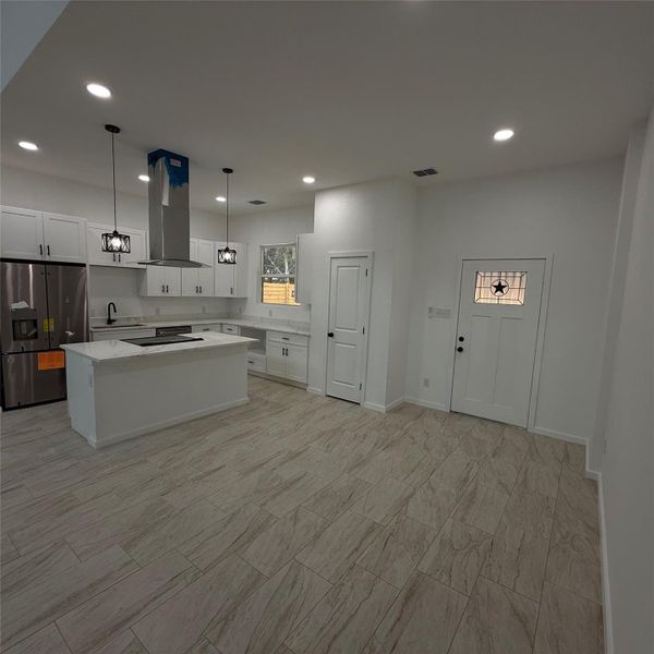 Modern kitchen featuring white cabinetry, a center island with cooktop, stainless steel appliances, recessed lighting, and pendant lights