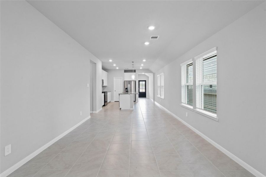 Enjoy meals in this sun-drenched space, featuring durable tile flooring, abundant natural light from the large windows (fitted with blinds), and recessed lighting.