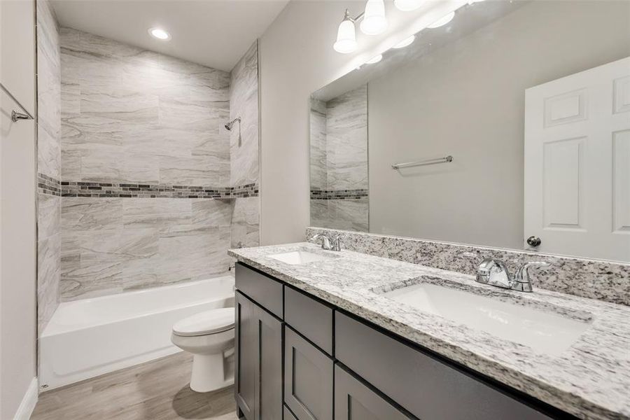 Full bathroom featuring vanity, tiled shower / bath combo, hardwood / wood-style floors, and toilet