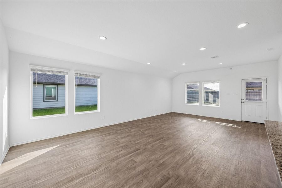 Spacious, bright living room with large windows, wood-like flooring, and recessed lighting.