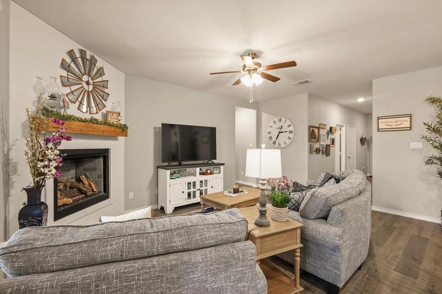 Living room with wood finished floors, a ceiling fan, and a glass covered fireplace Living room with wood finished floors, a ceiling fan, and a glass covered fireplace