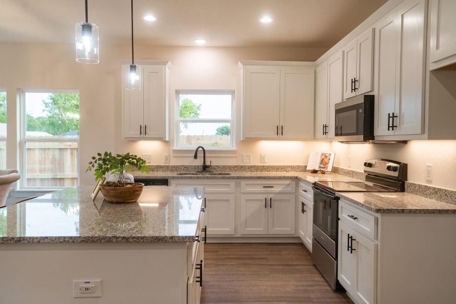 Kitchen featuring electric stove, a sink, healthy amount of natural light, white cabinets, and recessed lighting