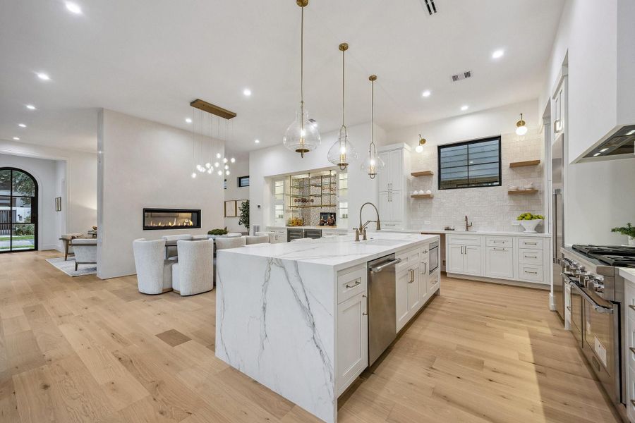 Kitchen Side Bar with 17" Kraus Undermount Single Basin Stainless Steel Sink, Single Hole Bar Faucet in Gold Luxe, Pre-Plumbing and Space for an Ice Maker, White Oak Floating Shelves with a Natural Stain, Brass Swing Arm Wall Sconce with Frosted Globes.