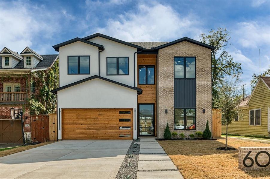 Contemporary house featuring concrete driveway, stucco siding, a gate, a garage, and brick siding Contemporary house featuring concrete driveway, stucco siding, a gate, a garage, and brick siding
