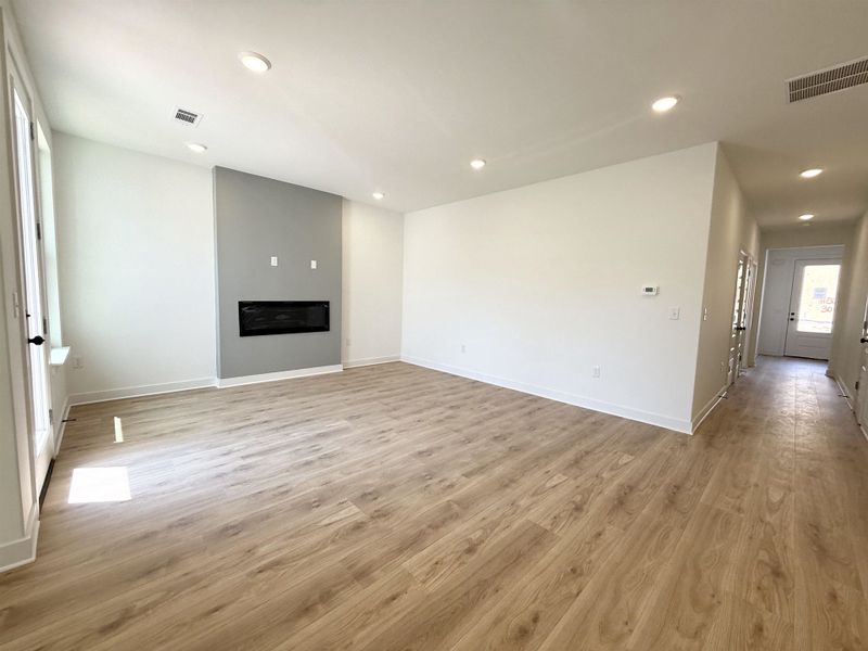 Unfurnished living room with light wood-type flooring, recessed lighting, and a glass covered fireplace