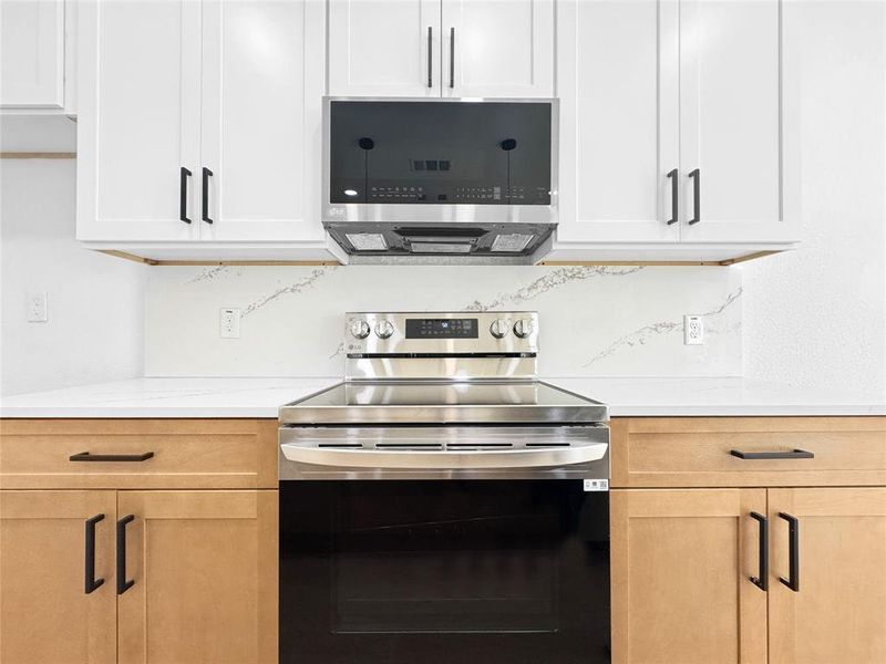 Kitchen featuring stainless steel appliances and light stone counters