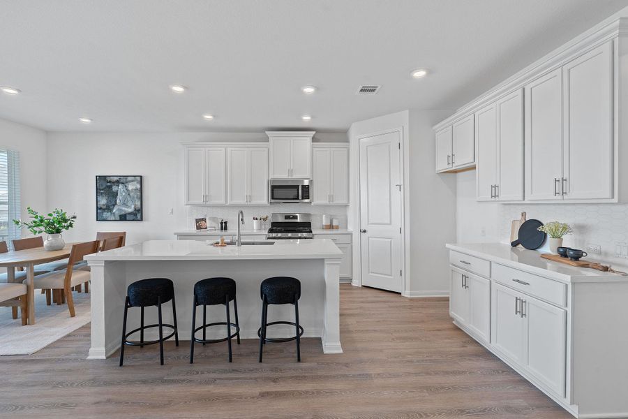 Kitchen featuring stainless steel appliances, a sink, white cabinetry, a kitchen bar, and recessed lighting
